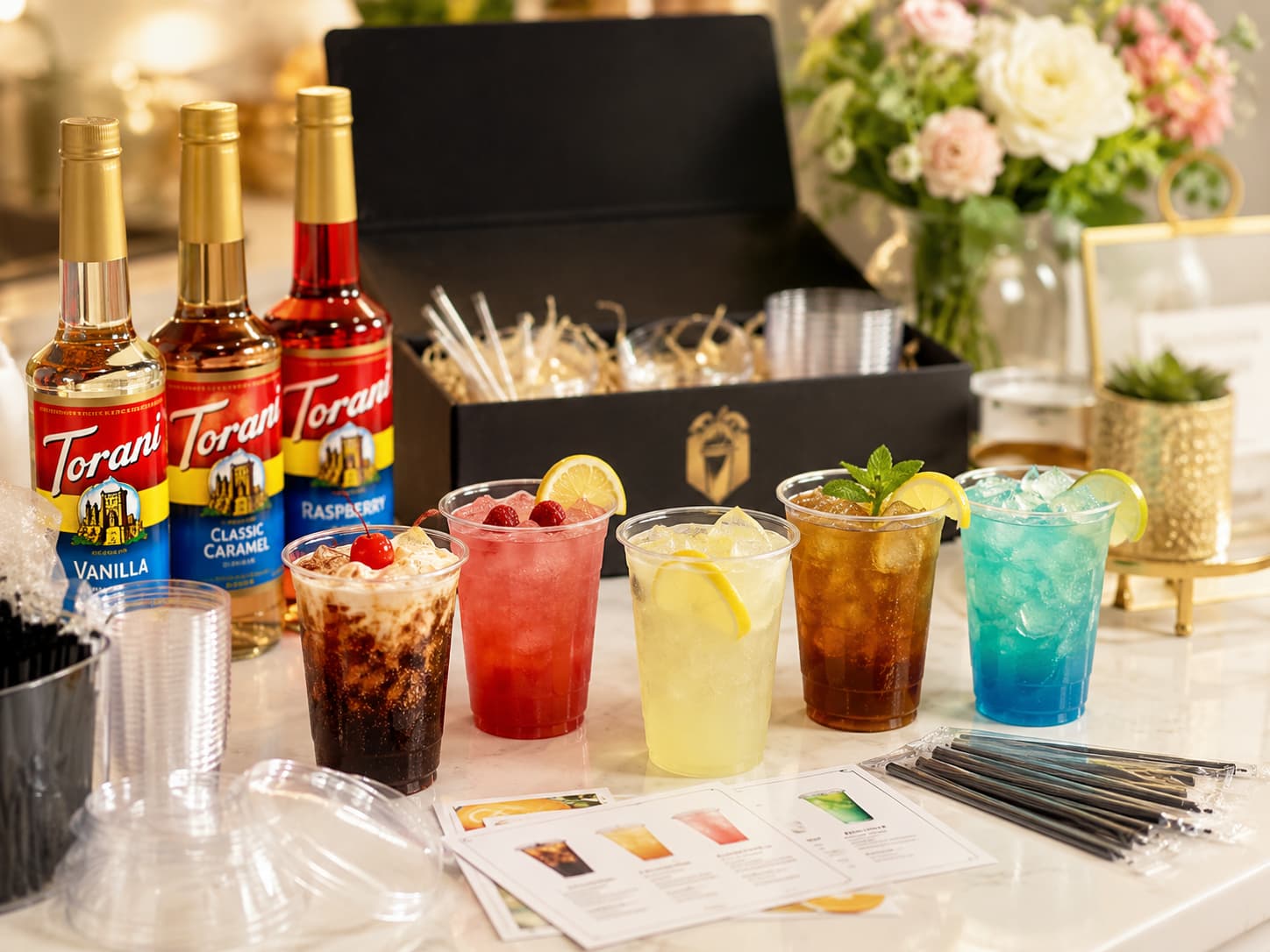 Drink Party Kits setup with alcohol-free drinks, Torani syrups, cups, straws, recipe cards and event supplies
